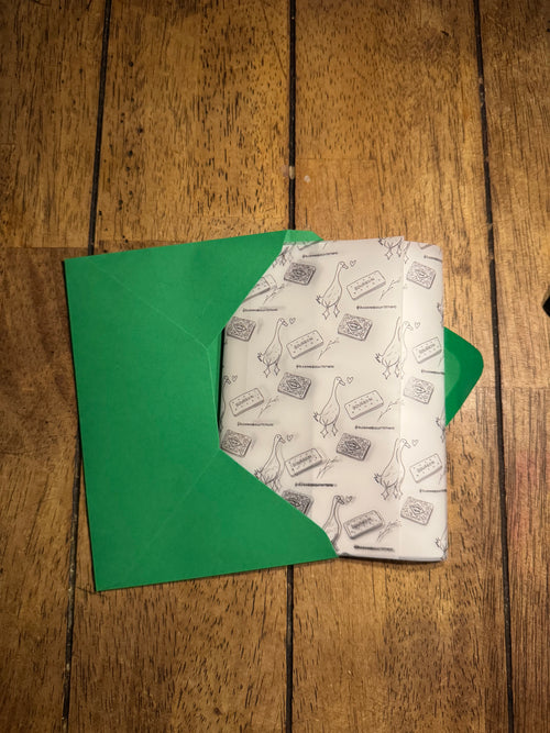 Green envelope with a patterned paper inside on a wooden surface