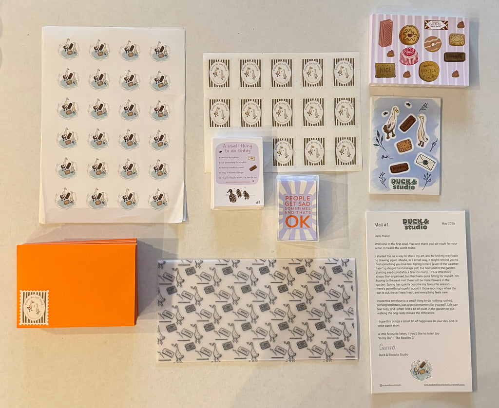 Collection of stationery items including cards, stickers, and an orange box on a beige background