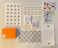 Collection of stationery items including cards, stickers, and an orange box on a beige background